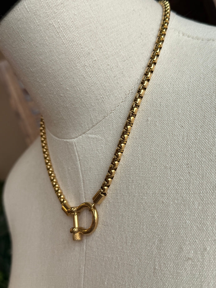 Close-up of gold box chain necklace with D-ring pendant detail