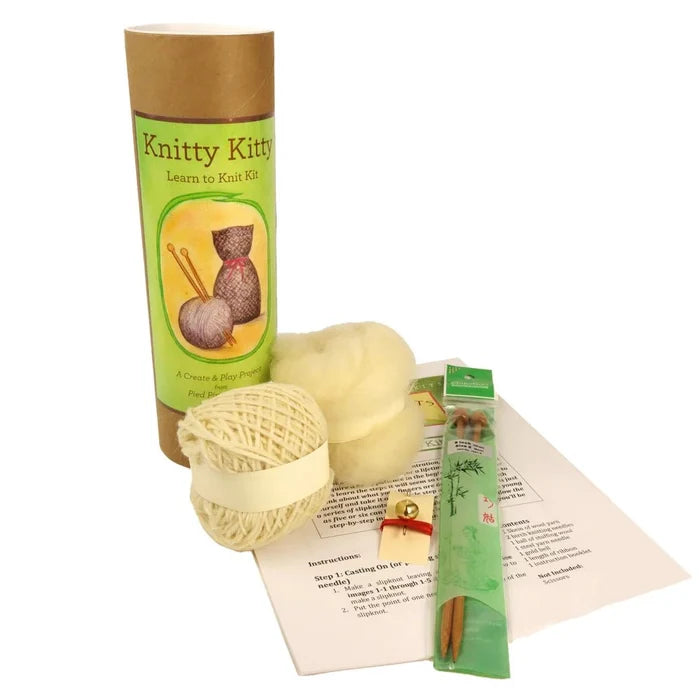 Knitting kit with yarn, needles, and instructions on a white background