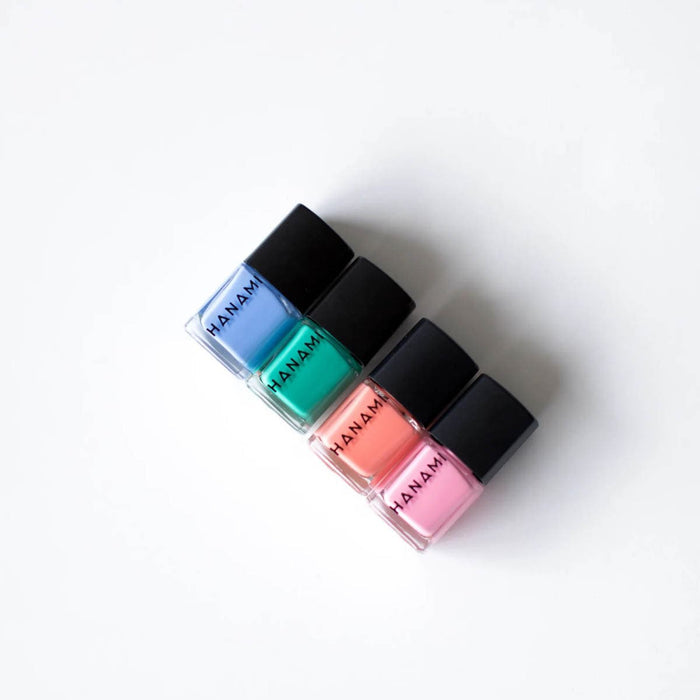 Four bottles of Manam nail polish in blue, green, pink, and red on a white background