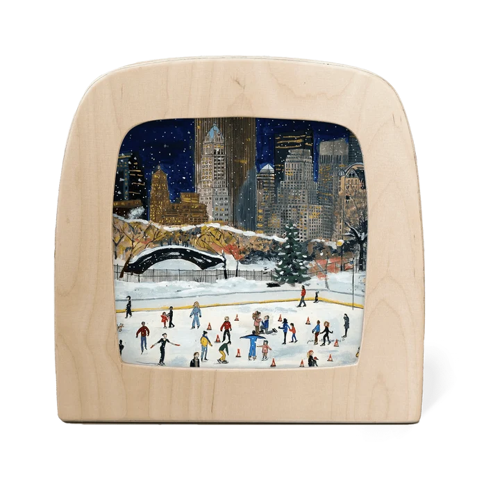 Wooden frame with silhouette of a New York cityscape in winter with people ice skating below