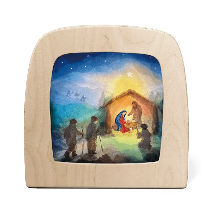 Wooden frame with a silhouette of a Nativity scene featuring Mary, Joseph, baby Jesus, the three wise men, and others gathered around the manger