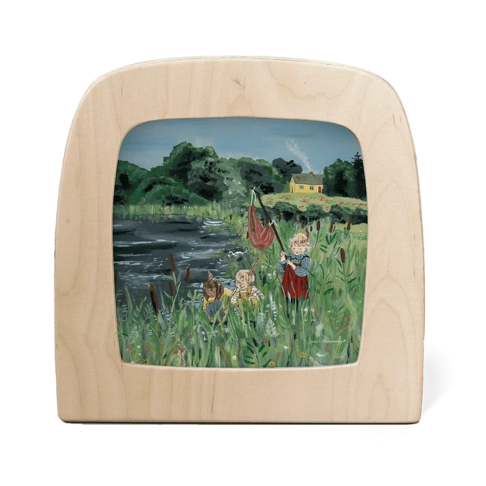 three children play by the lake with lush green trees and a yellow house in the background