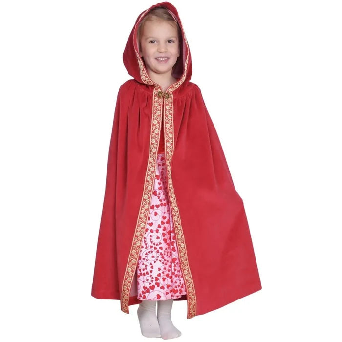 Child wearing a red hooded cape with a ribbon trim over a patterned dress on a white background