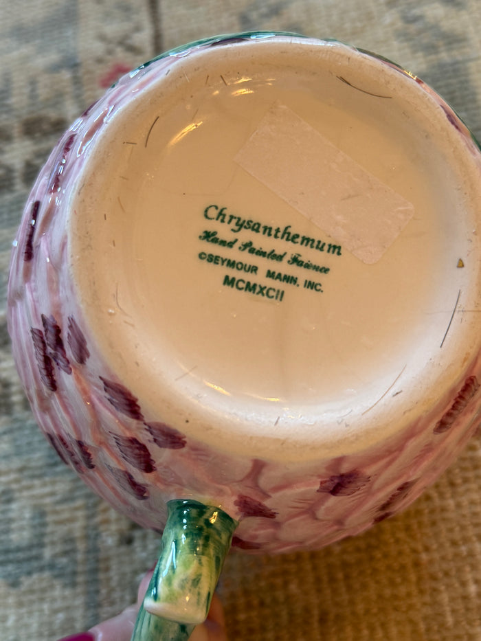 Close-up of a ceramic mug with floral patterns and text on a textured surface.