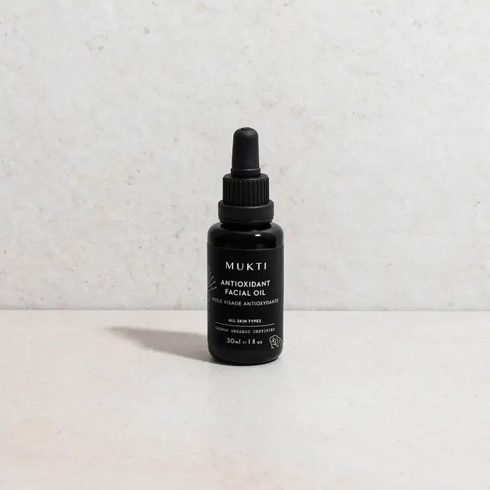 MUKTI facial oil dropper bottle styled on a stone surface and background.