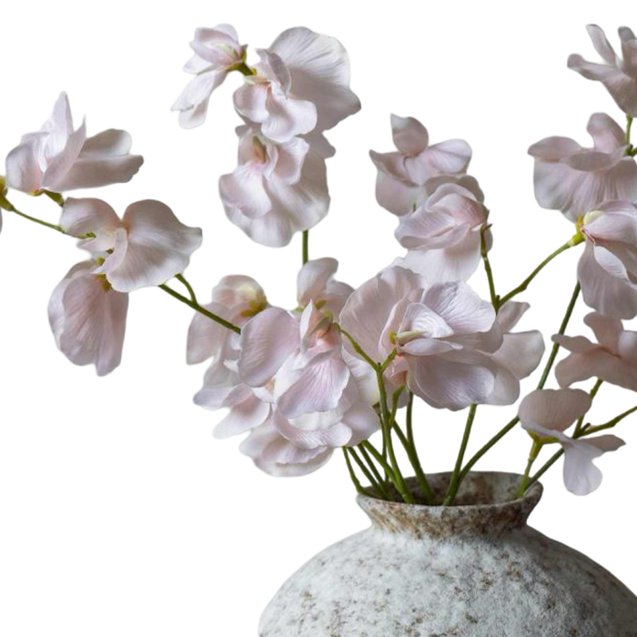 Pink artificial orchids in a textured vase on a white background