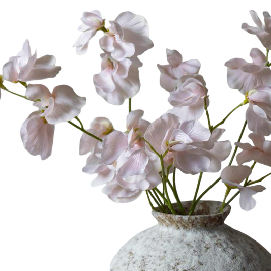 Pink artificial orchids in a textured vase on a white background