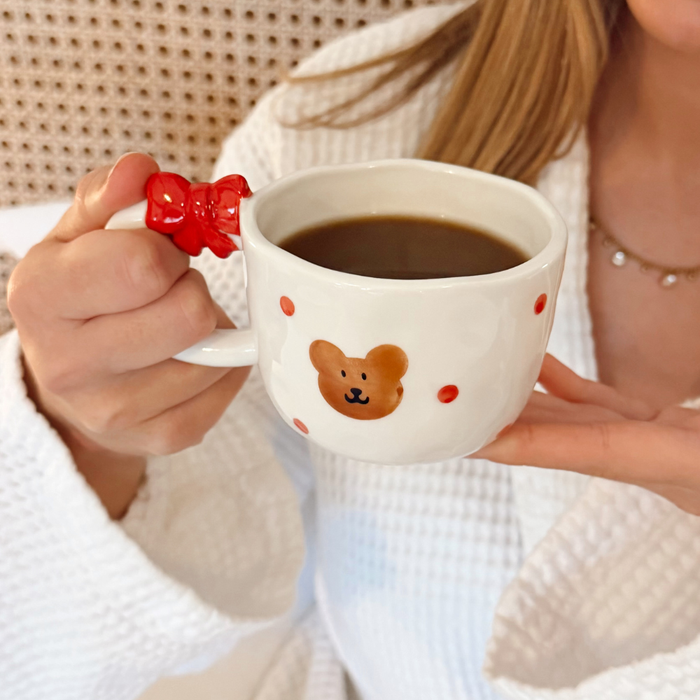 Woman in white robe holds Coconut Lane Beary Cute Mug and Toast Plate Set with red dots and bear face design.