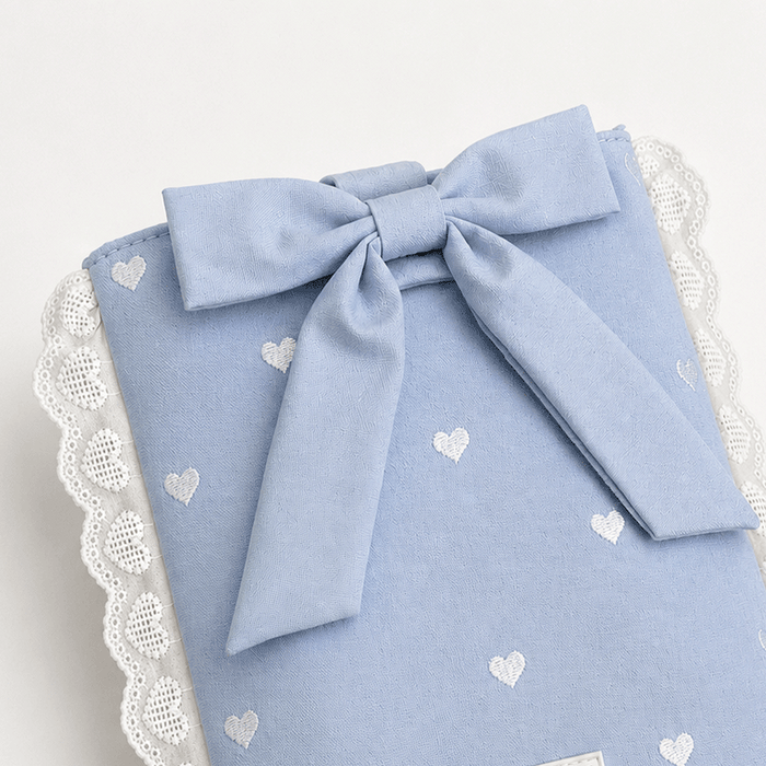 Blue fabric Book Sleeve with embroidered heart design, bow closure and white lace edging.