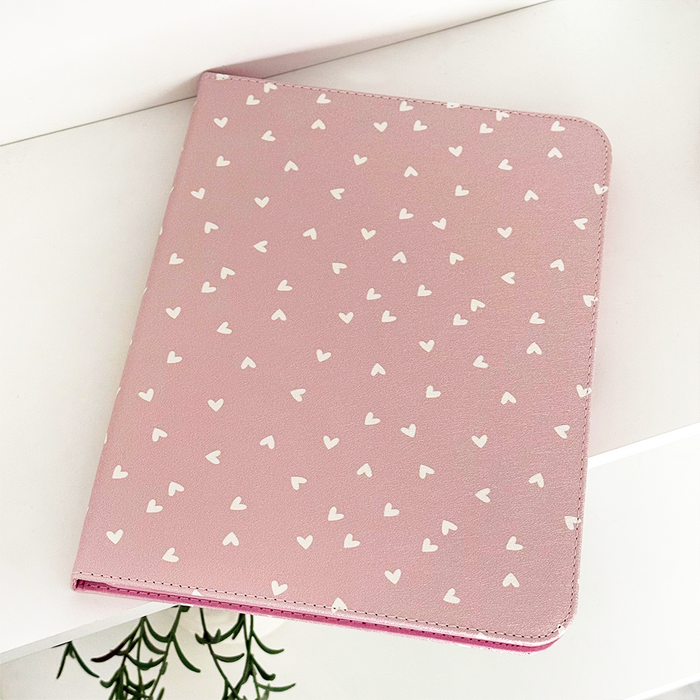 Pink vegan leather iPad case with a pattern of white hearts.