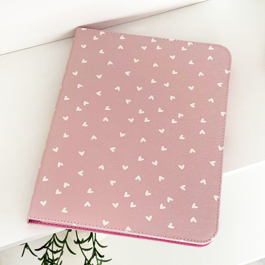 Pink vegan leather iPad case with a pattern of white hearts.