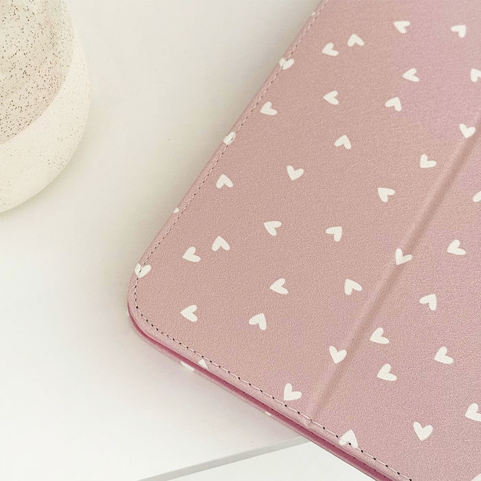 Coconut Lane Chai Hearts iPad case with white heart pattern beside a speckled ceramic cup on a white surface.