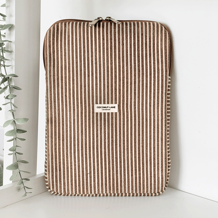 Chestnut striped iPad sleeve by Coconut Lane, with towel-like texture, displayed near a plant on a white shelf.