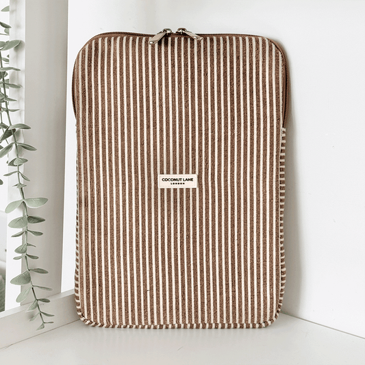 Chestnut striped iPad sleeve by Coconut Lane, with towel-like texture, displayed near a plant on a white shelf.