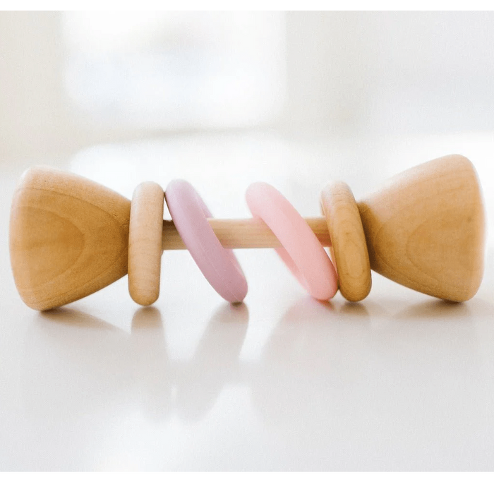 Wooden baby rattle with pink and purple accents on a white background