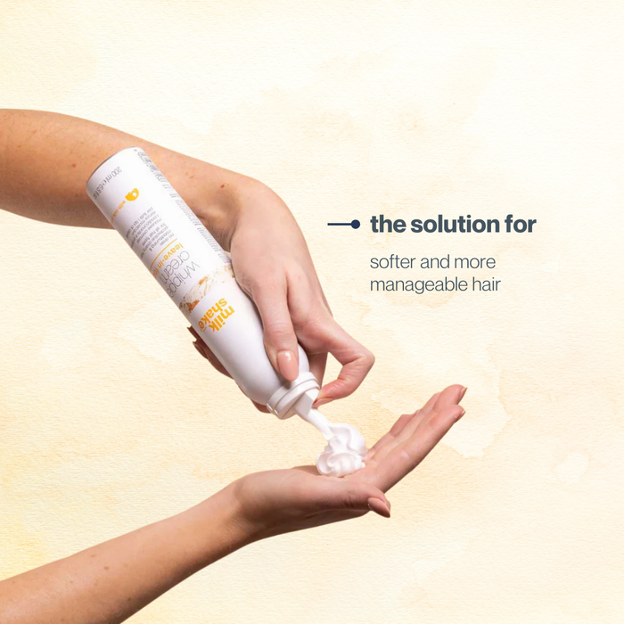 Hand applying milk_shake whipped cream with text 'the solution for softer and more manageable hair' on a beige background.