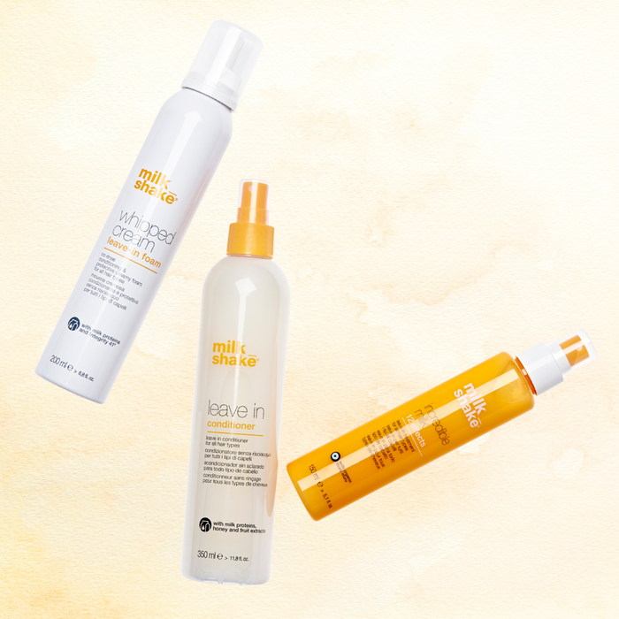 Three bottles of milk_shake  hair care products on a light yellow background