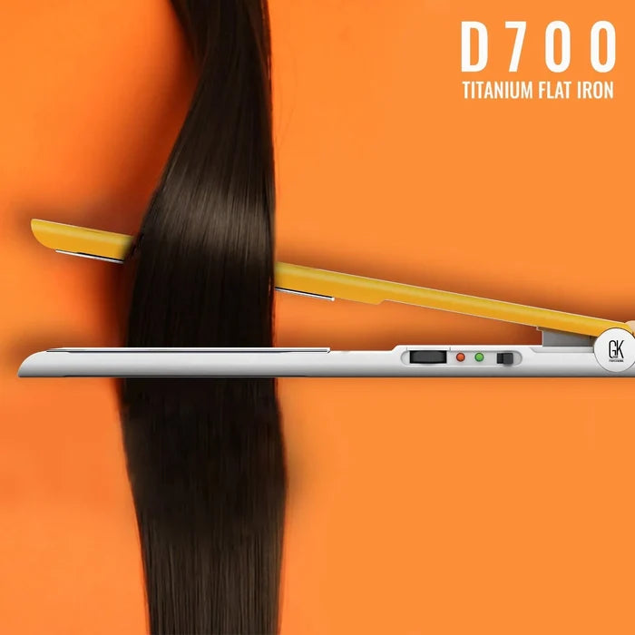 GK Hair D700 Titanium Flat Iron clamping a long straight dark brown hair section against an orange background