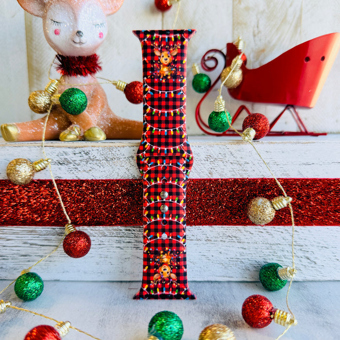 Close-up of Deerlightful reindeer print with festive lights on red and black buffalo check Apple Watch silicone band