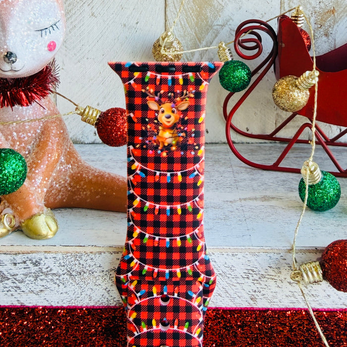 Close-up of Deerlightful reindeer print with festive lights on red and black buffalo check Apple Watch silicone band