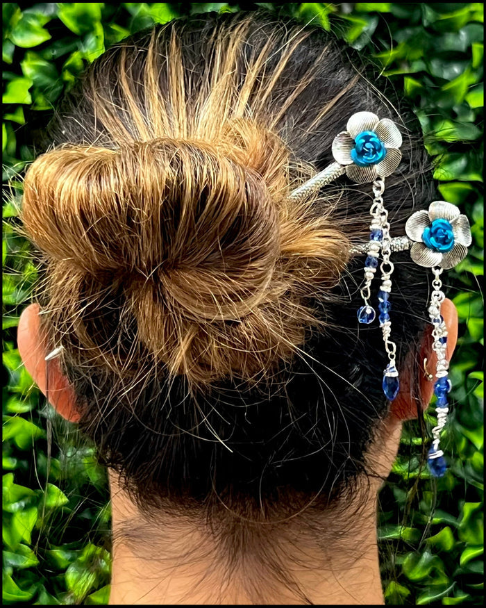 Model wearing Flower & Bead Hair Sticks with blue floral accents and dangling beads in a bun hairstyle.