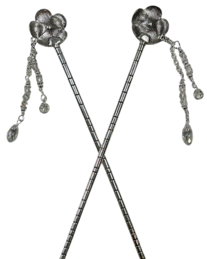 Pair of silver flower hair sticks with crystal bead dangle chains, shown crossed on a white background to display the back view and floral design.