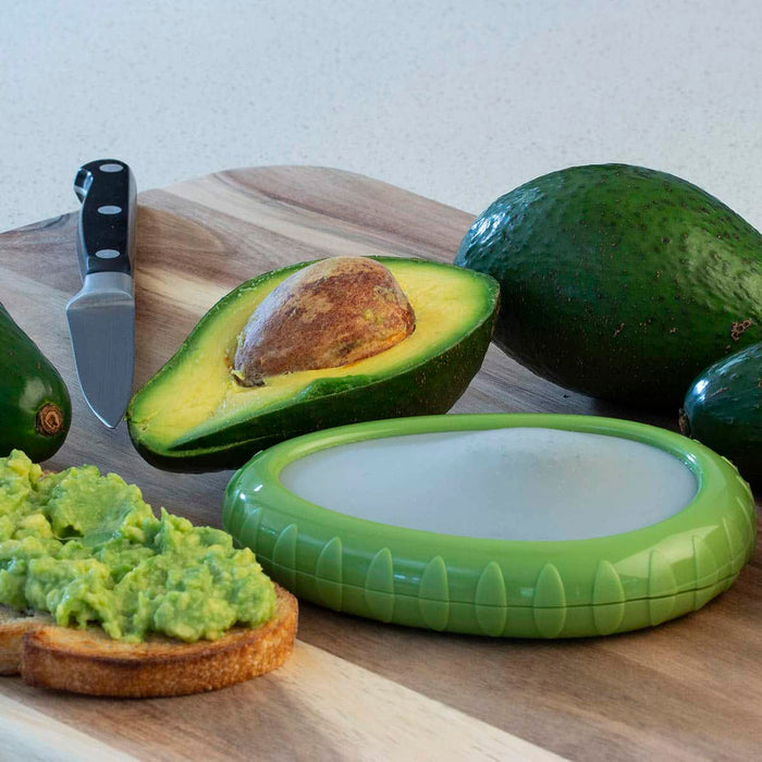 Avocado on a wooden cutting board with a knife, half-cut avocado, whole avocado, and guacamole on toast.