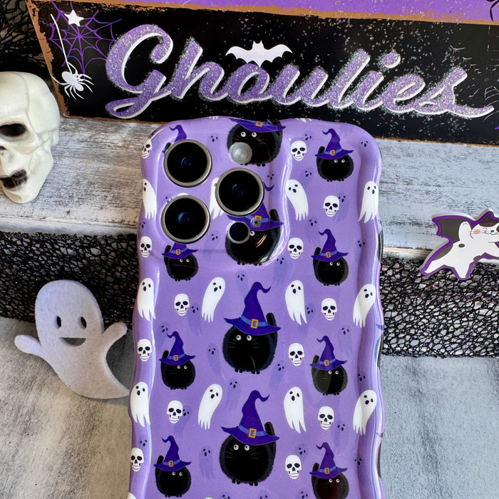 Ghostly Whisker's Wavy Luxe MagSafe iPhone case angled in front of a HELLO Ghoulies sign with a white skull and purple bat prop.