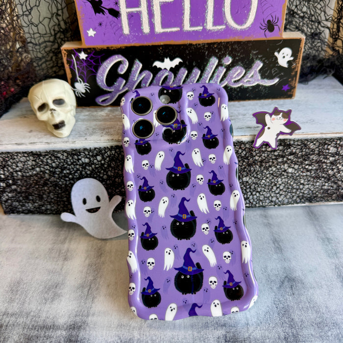 Ghostly Whisker's Wavy Luxe MagSafe iPhone case standing upright beside a white skull and a small ghost figurine on a Halloween set.