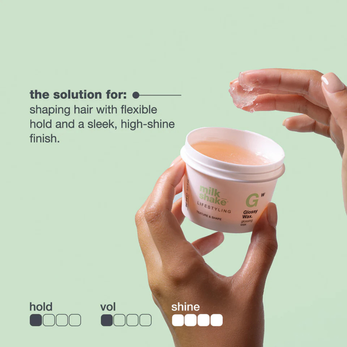 Hand holding a container of milk_shake glossy wax with text on a light green background