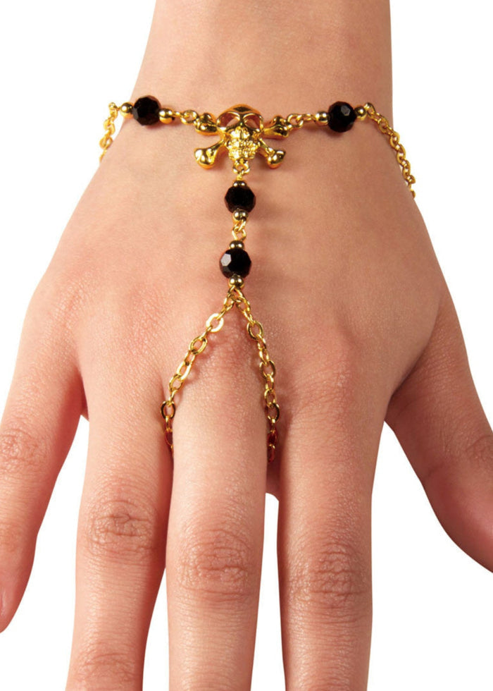 Gold skull and crossbones hand chain finger bracelet with black bead accents worn on hand
