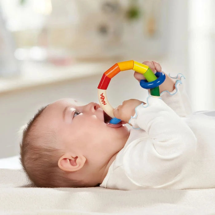 Baby playing with a colorful toy ring on a blurred background