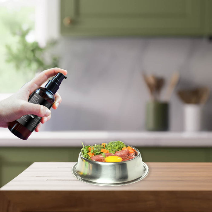 Person holding a spray bottle over a bowl of food on a kitchen counter.