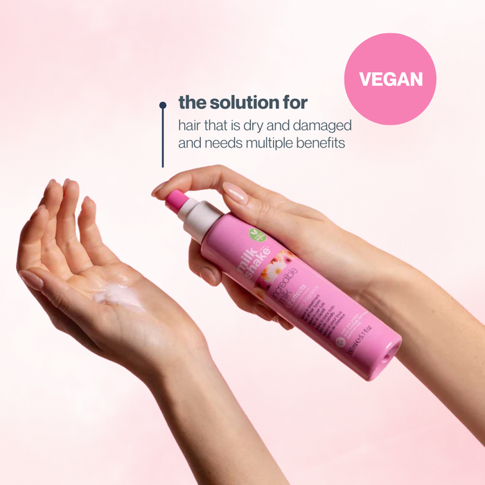 milk_shake hair care product being held with a hand, on a pink background with 'VEGAN' label.