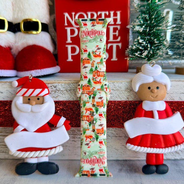 North Pole Apple Watch band with Santa's workshop, Christmas trees, and reindeer on cream background with North Pole sign