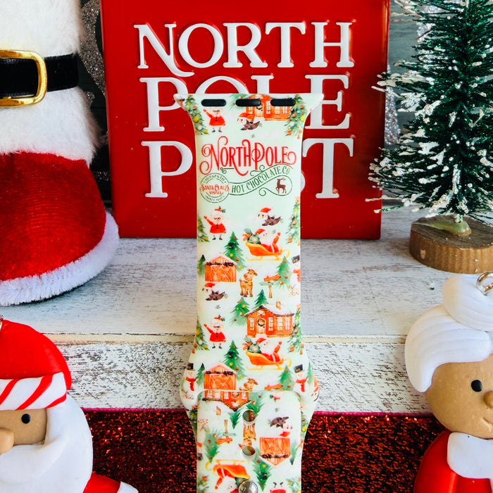 North Pole Apple Watch band with Santa's workshop, Christmas trees, and reindeer on cream background with North Pole sign