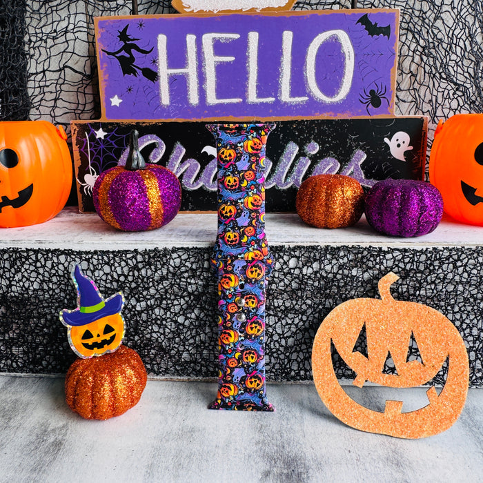 Single Jack-O-Lantern Jive Apple Watch band strap standing in front of a HELLO Ghoulies sign with a witch-hat pumpkin prop.