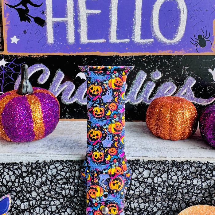 Close-up of the Jack-O-Lantern Jive Apple Watch band showing glowing pumpkins, lavender ghosts and crescent moons on deep violet.