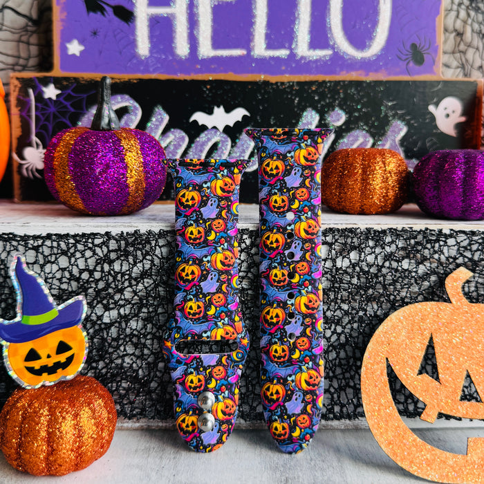 Two Jack-O-Lantern Jive Apple Watch band straps standing side by side beside a jack-o-lantern wearing a purple witch hat.