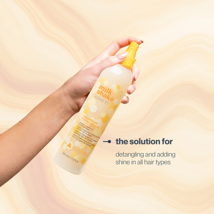 Hand holding a bottle of 'milk shake' honey infused leave in conditioner with text on a beige background