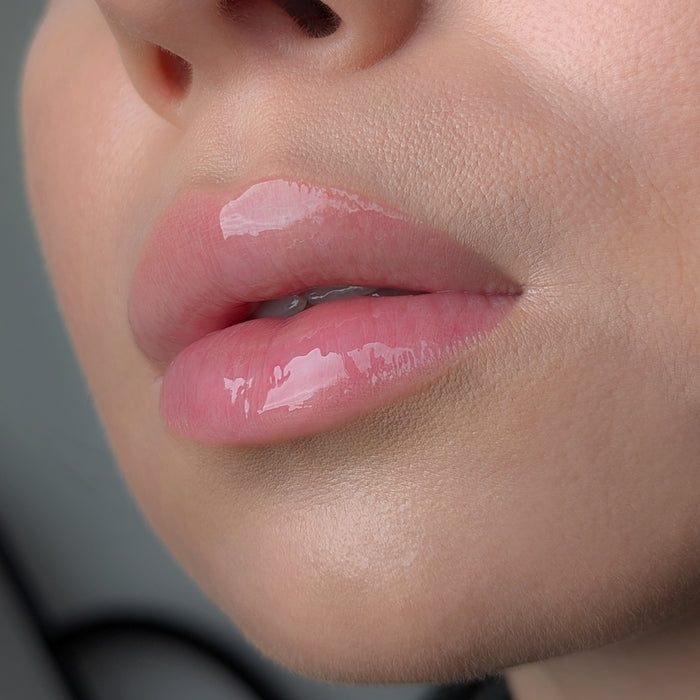 Close-up of a person's lips with a glossy lip gloss Lipss Kyiv Cake on a neutral background