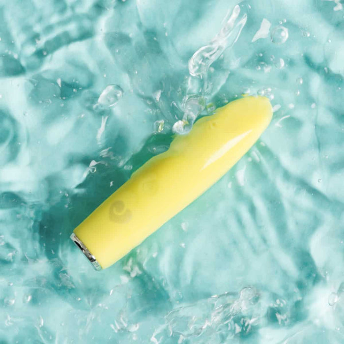 Yellow bullet massager partially submerged in clear blue water.