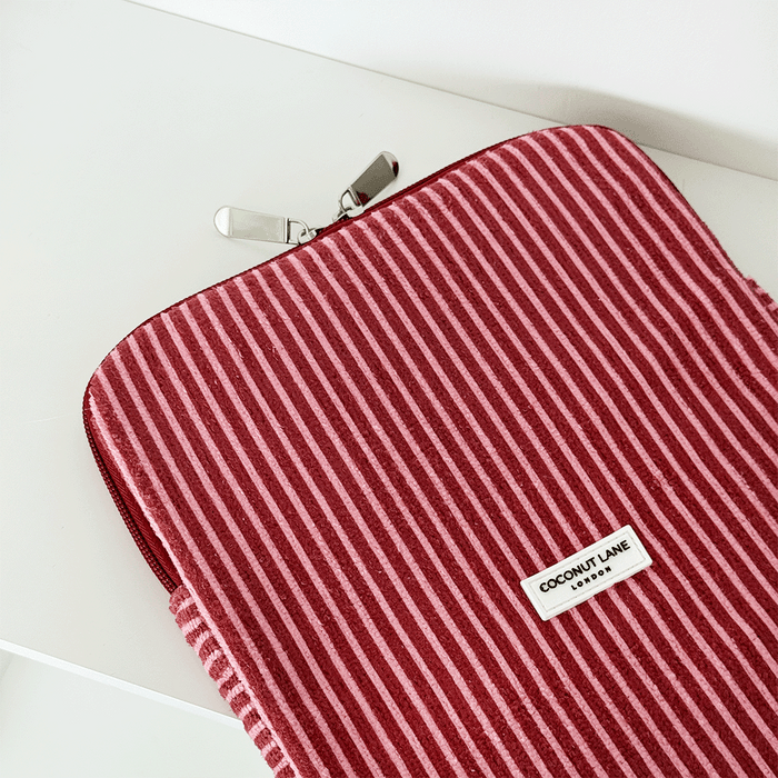 Pink quilted iPad sleeve with mulberry stripes and zipper, by Coconut Lane, shown on a white surface.