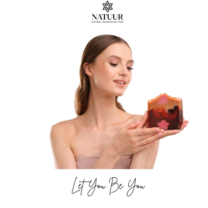 A woman holding a Natuur.in beetroot, carrot, and rose skin brightening soap bar with decorative botanical embeds.
