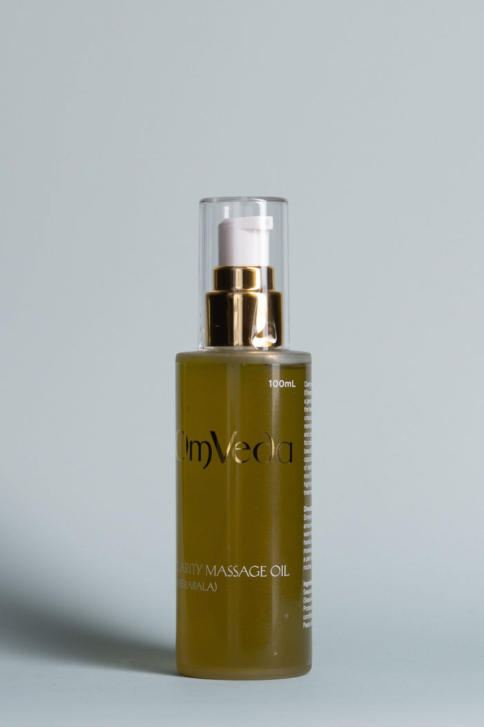 OmVeda clarity body oil bottle, clear pump top over dark amber oil