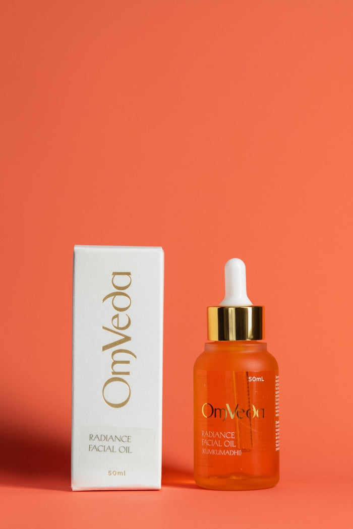 OmVeda Radiance facial oil set: amber dropper bottle with gold cap and box.