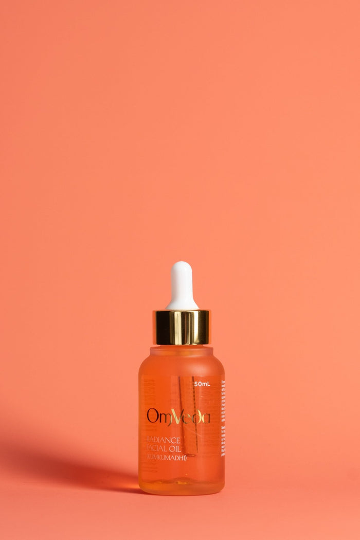 OmVeda Radiance facial oil dropper bottle with amber liquid and gold cap.