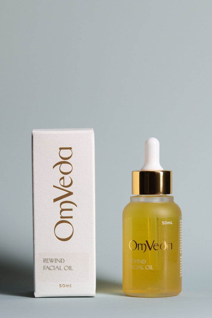 OmVeda Rewind facial oil bottle with dropper and 50 ml box, amber-gold glass