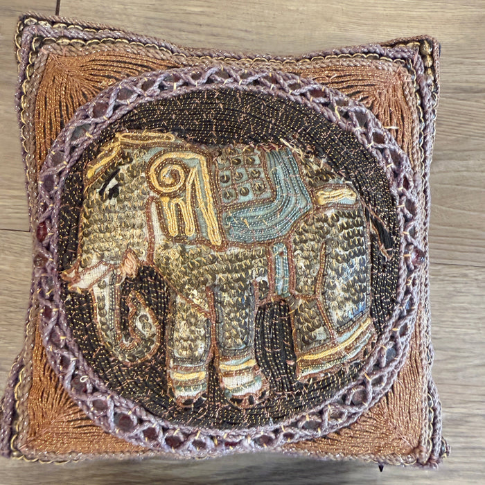Decorative pillow with intricate beadwork on a wooden surface