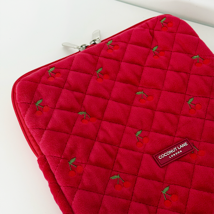 Quilted velvet iPad sleeve in red with cherry print pattern and a Coconut Lane label on the front.